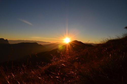 a sunset on the top of a hill with grass at Hotel Chalet Dlaces in Selva di Val Gardena