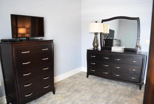 a bedroom with a dresser with a tv and a mirror at JH Adams Inn, Trademark Collection by Wyndham in High Point