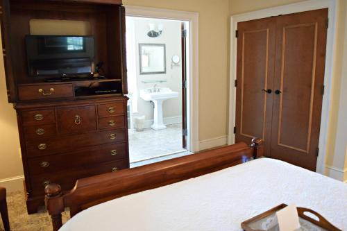 a bedroom with a bed and a dresser with a television at JH Adams Inn, Trademark Collection by Wyndham in High Point