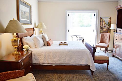 a bedroom with a bed and a chair and a window at JH Adams Inn, Trademark Collection by Wyndham in High Point