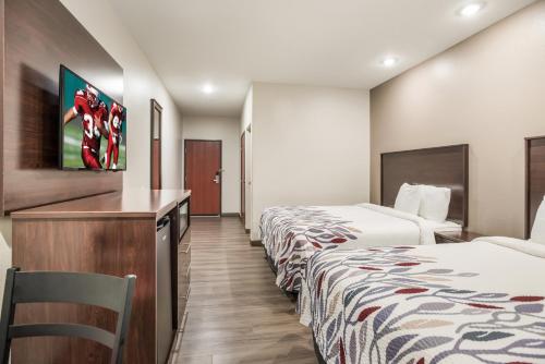 a hotel room with two beds and a desk at Red Roof Inn & Suites Lake Charles in Lake Charles