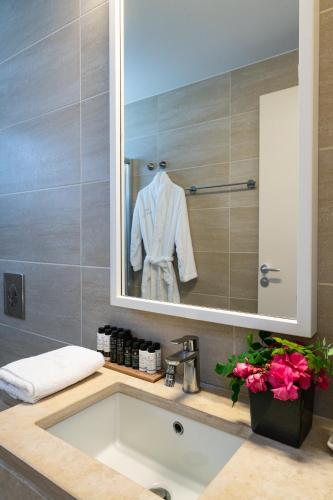 a bathroom with a sink and a white robe in a mirror at Sofia Luxury Villas in Panormos Rethymno