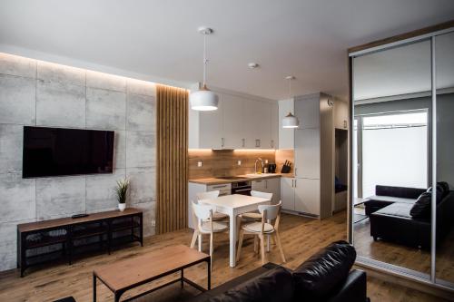 a living room and kitchen with a table and a couch at Shipyard Gdańsk Apartment - free private parking in Gdańsk