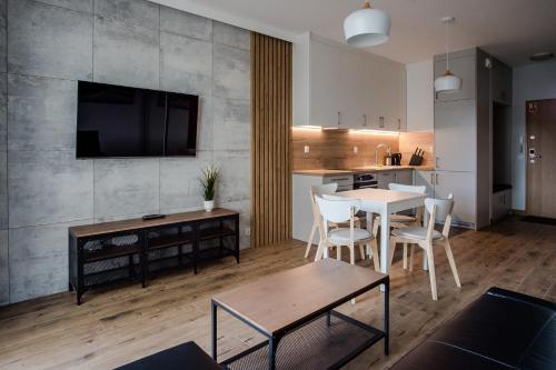a living room with a dining table and a kitchen at Shipyard Gdańsk Apartment - free private parking in Gdańsk