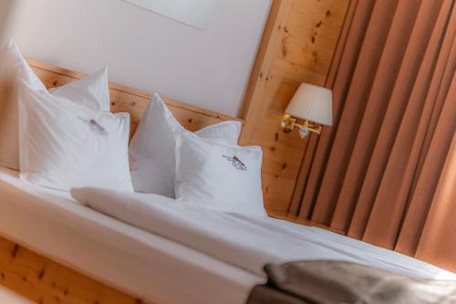 a bedroom with a bed with white pillows at Hotel Chalet Dlaces in Selva di Val Gardena