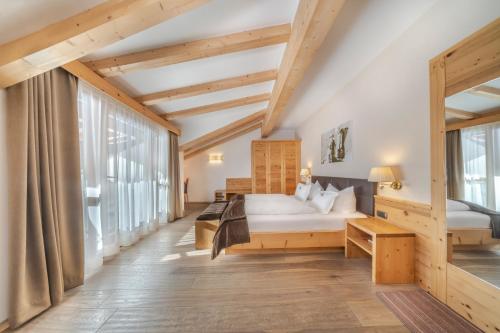 ein Schlafzimmer mit einem Bett und einem großen Fenster in der Unterkunft Hotel Chalet Dlaces in Wolkenstein in Gröden
