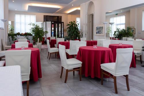 a dining room with red tables and white chairs at Hotel La Nuova Rotaia in Gallarate