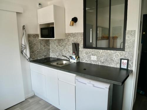 eine Küche mit einem Waschbecken und einem Spiegel in der Unterkunft Plage Cabourg 5bis in Cabourg
