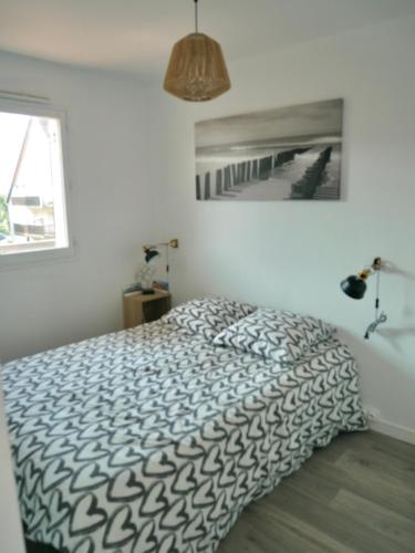 une chambre avec un lit avec une couette noire et blanche dans l'établissement Plage Cabourg 5bis, à Cabourg