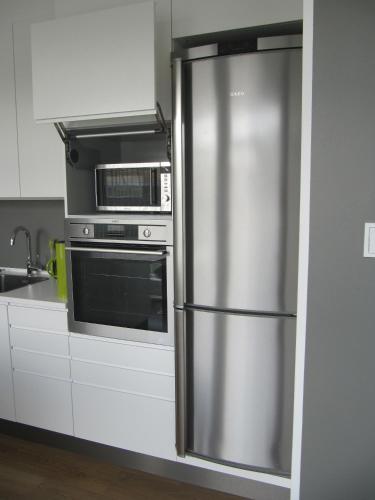 a kitchen with a stainless steel refrigerator and a microwave at Seydisfjördur Apartment in Seyðisfjörður