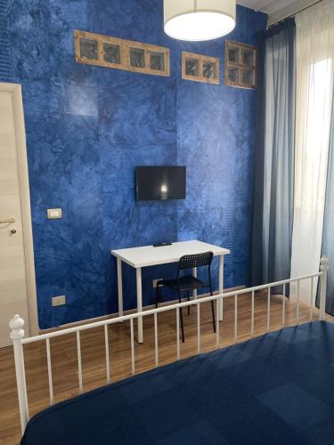 Habitación con mesa y TV en una pared azul. en B&B Acqua Azzurra en Castellammare di Stabia