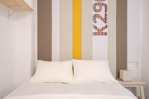 a bedroom with a white bed with a striped wall at NICE and COSY LOFTS CITY CENTER 1&2 in Málaga