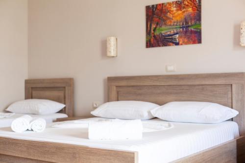two beds with white pillows and a painting on the wall at Toni Retzo Rooms in Himare
