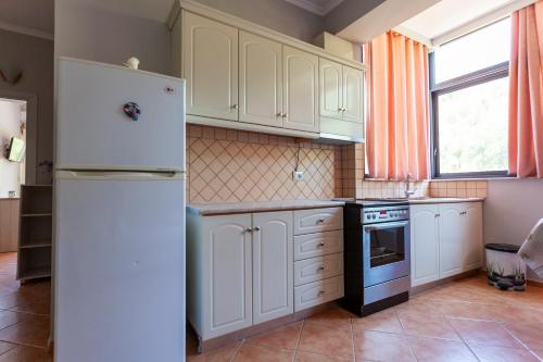 a kitchen with white cabinets and a white refrigerator at Toni Retzo Rooms in Himare