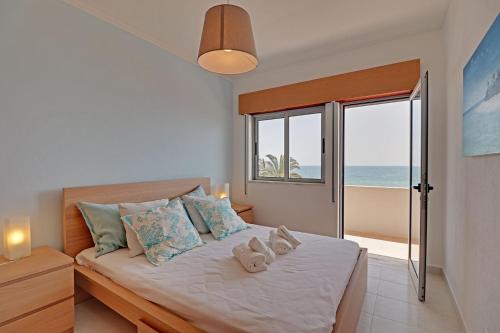 a bedroom with a bed with a view of the ocean at Quarteira Beach & Ocean View by Homing in Quarteira
