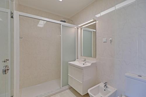 a white bathroom with a sink and a shower at Quarteira Beach & Ocean View by Homing in Quarteira