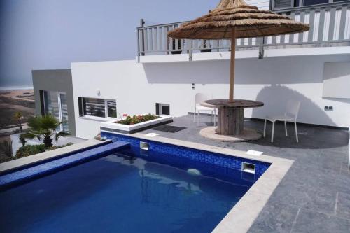 a pool with an umbrella and a table and a table with an umbrella at 2 bungalows avec vue sur mer et piscine PARTAGEE in Oualidia