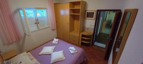 Dormitorio pequeño con cama morada y espejo en Zvjezdana en Kampor