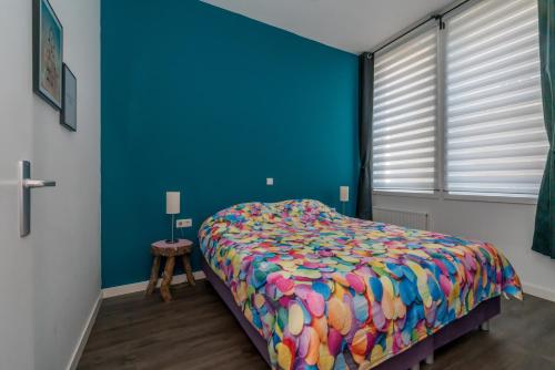 a bedroom with a bed with a colorful comforter at Slapen bij Van-V in Zierikzee