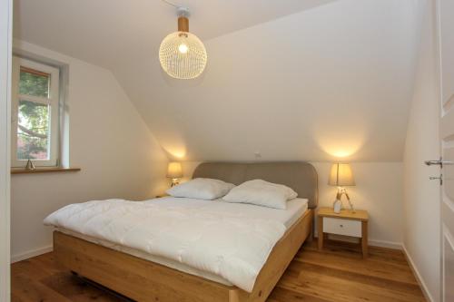 a bedroom with a bed with white sheets and two lamps at Schilfkante - Am Ufer in Wieck