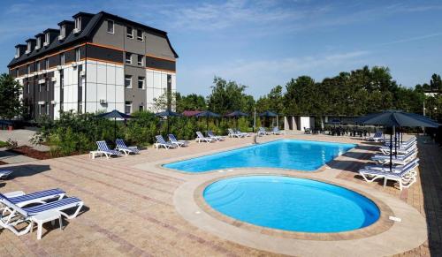 a hotel with a pool and chairs and a building at Аквамарин in Gribovka
