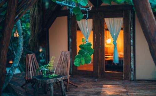 a room with two chairs and a door with a plant at Glamp Ikal Tulum in Tulum