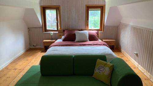 a bedroom with a green bed with two windows at Familien Ferienhaus in Bad Elster Vogtland - Natur pur und Wellness in Bad Elster