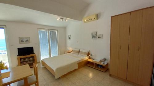 um quarto com uma cama, uma secretária e uma televisão em Apartmani Antonini 2 em Živogošće