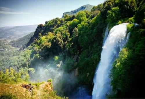 a waterfall in the middle of a mountain with trees at Torre Paola Dimora romantica in Acquasparta