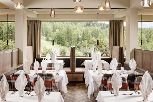 a restaurant with white tables and chairs and large windows at Sporthotel Obereggen in Obereggen