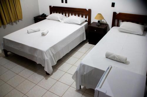 two beds in a room with white sheets and pillows at Polo Hotel Fazenda in Indaiatuba