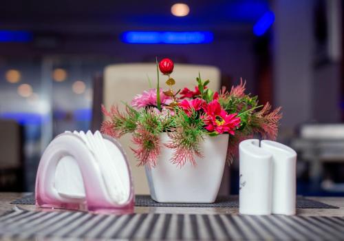 a vase with flowers in it sitting next to a napkin at Presken Hotel and Resorts MOJIDI in Ikeja