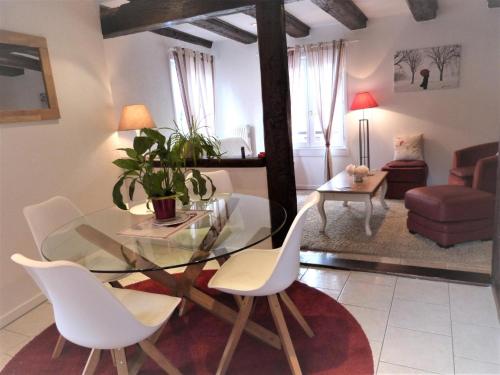 une salle à manger avec une table en verre et des chaises blanches dans l'établissement Gites Aux Fines Bulles d'Alsace SPA privatif en supplément, à Bergheim