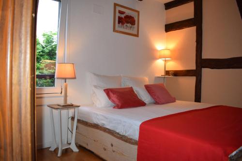 um quarto com uma cama com almofadas vermelhas e uma janela em Gites Aux Fines Bulles d'Alsace SPA privatif en supplément em Bergheim