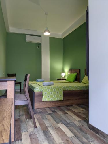 a green bedroom with a bed and a table at Hotel Paradise Road in Kutaisi