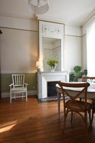 a living room with a fireplace and a table and a mirror at La maison botanique in Castillon-la-Bataille