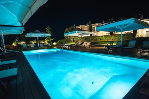 a swimming pool at night with umbrellas at Calas Sani Villas in Filakaí Kassándras