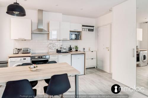 une cuisine avec des armoires blanches et une table en bois dans l'établissement Hyper central studio 2 minutes walk from 