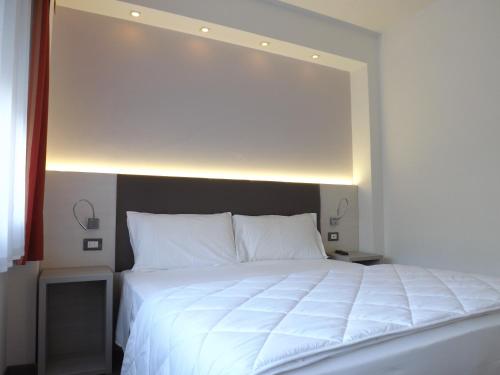 a bedroom with a large white bed with a light above it at Hotel Ariston in Bolzano