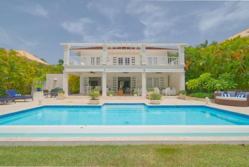 Villa con piscina frente a una casa en Cozy 4BDR villa in luxury beach resort with service staff and view of La Cana golf course, en Punta Cana