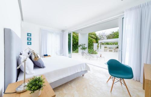 1 dormitorio blanco con 1 cama y 1 silla azul en Luxury 5-room modern villa with movie theater at exclusive Punta Cana golf and beach resort, en Punta Cana