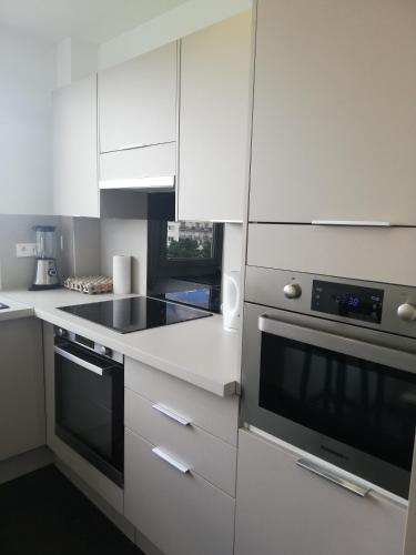 une cuisine avec des armoires blanches et un four à plaques de cuisson dans l'établissement Quiet apartment, 12 mn from Paris, à Colombes