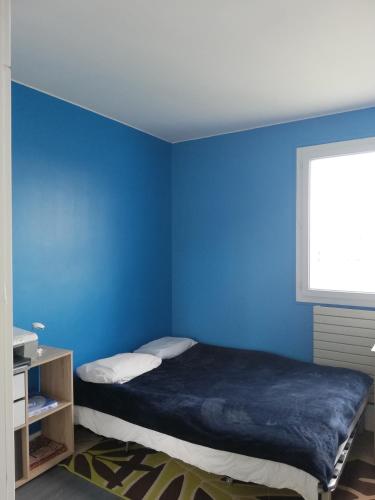 une chambre bleue avec un lit et une fenêtre dans l'établissement Quiet apartment, 12 mn from Paris, à Colombes