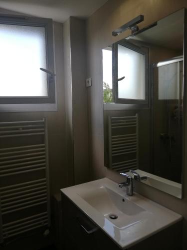 La salle de bains est pourvue d'un lavabo, d'un miroir et de 2 fenêtres. dans l'établissement Quiet apartment, 12 mn from Paris, à Colombes