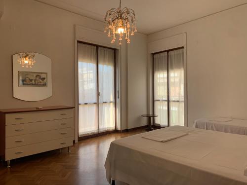 a bedroom with a bed and a dresser and windows at Spazioso appartamento in centro Città in San Benedetto del Tronto