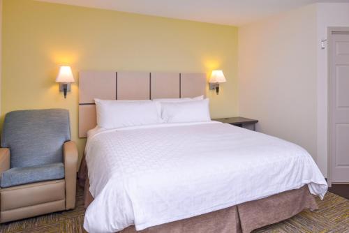 a bedroom with a large white bed and a blue chair at Candlewood Suites Paducah by IHG in Paducah