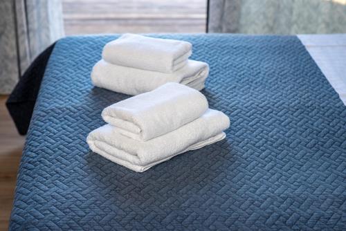 three towels are stacked on a blue table at Melcon Luxury Suites in Parga