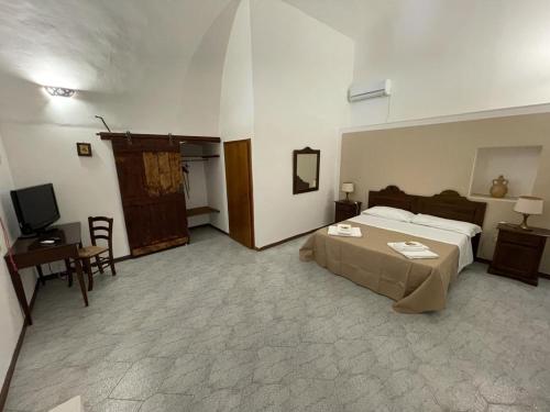 a hotel room with a bed and a television at Masseria Artemisia in Torre San Giovanni Ugento