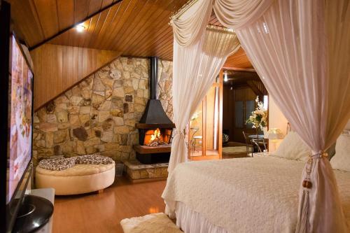 a bedroom with a bed and a stone fireplace at Pousada D'lines in Campos do Jordão