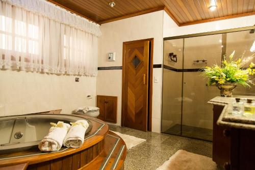 a bathroom with a tub and a shower with towels at Pousada D'lines in Campos do Jordão